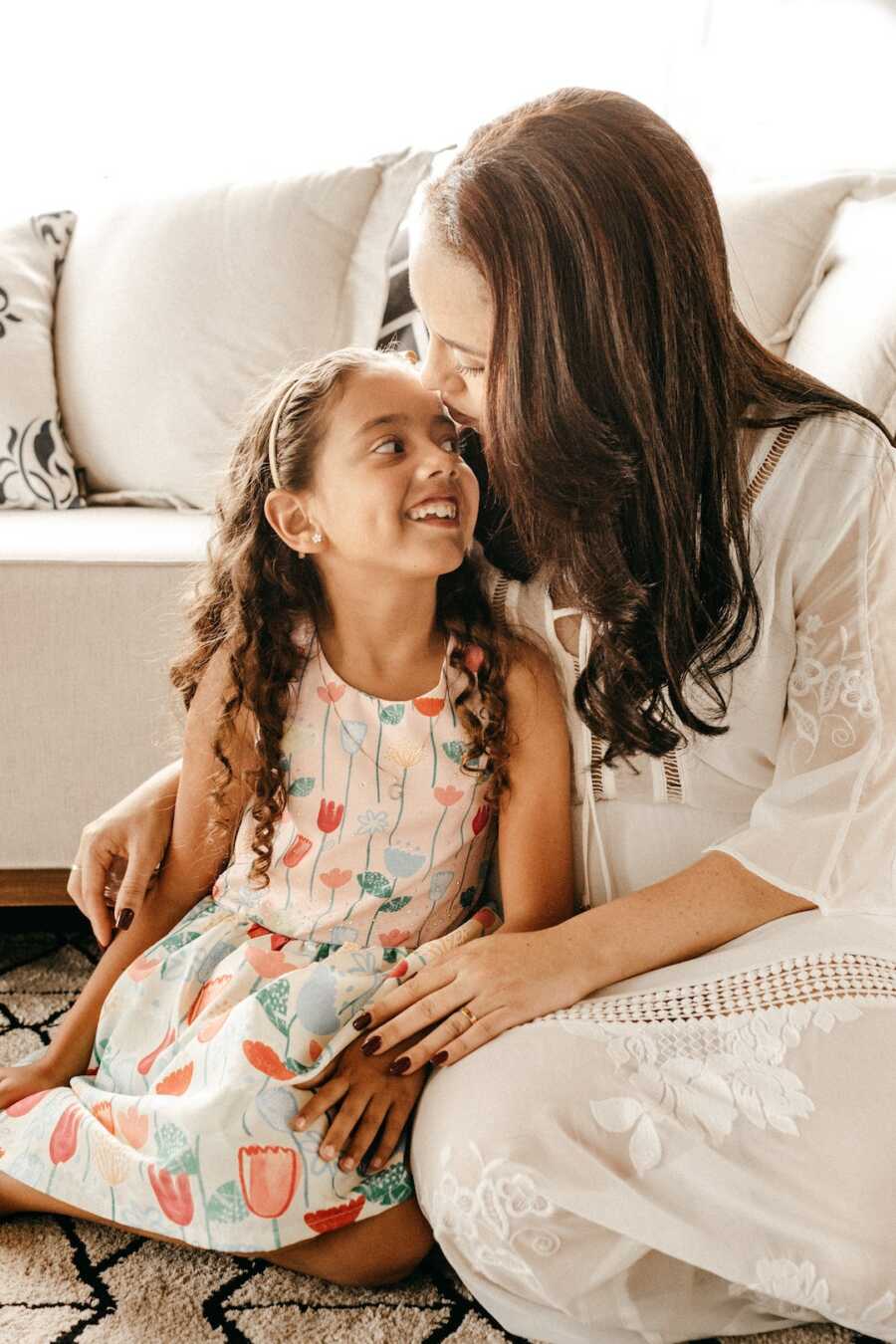 mother sits on floor with her daughter at her side