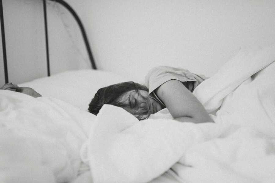 woman lays in bed with blankets napping