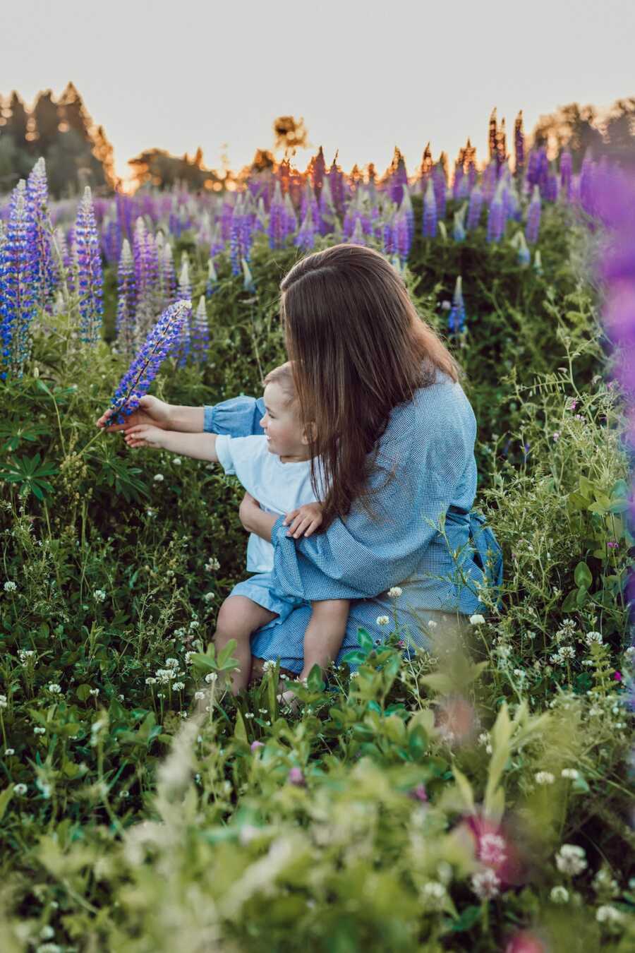 mom sits with her child in a field of flowers