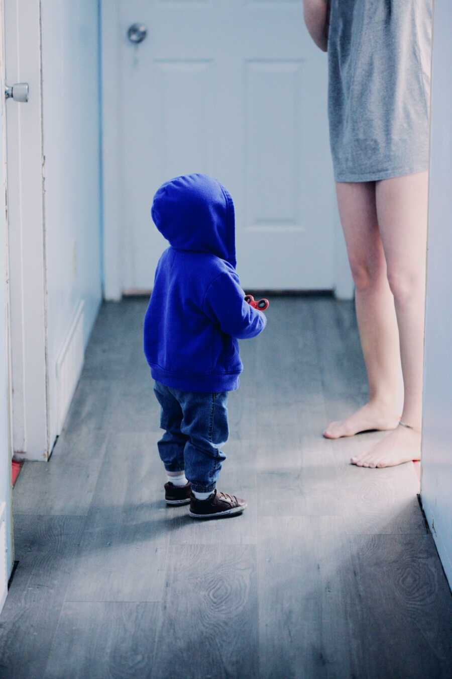 mother stands in doorway while child stands in front of her looking up
