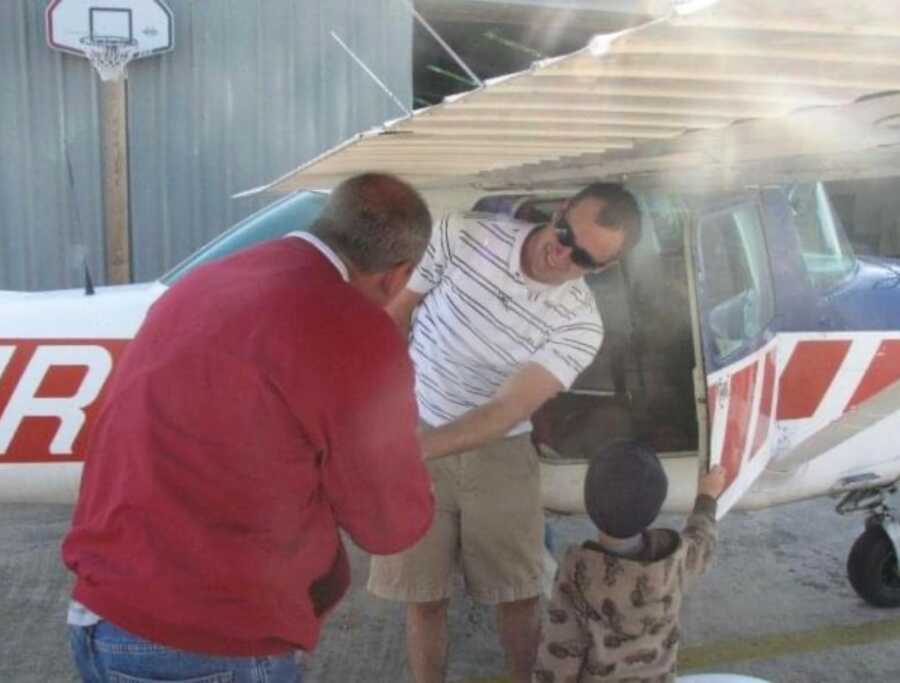 Man meeting with OU flight professor shakes hands under the wing of an airplane. 