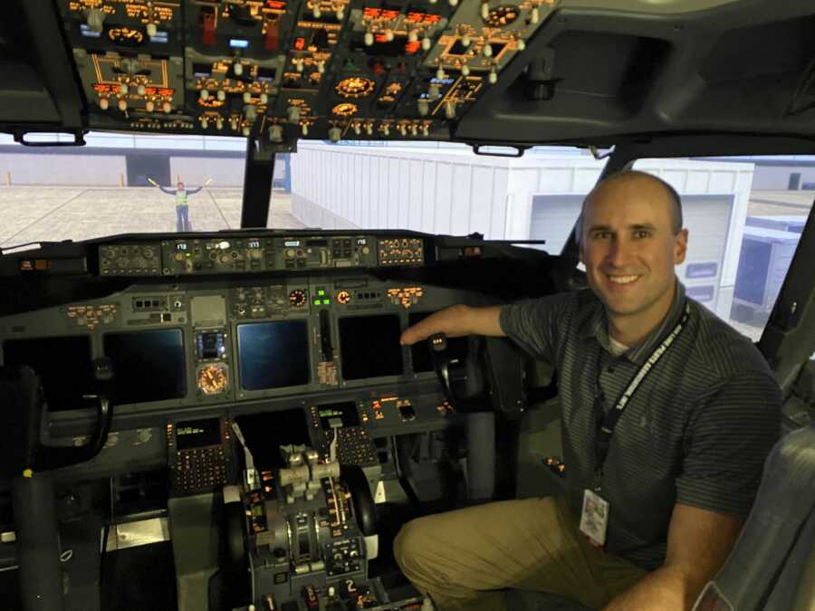 Man sits in the cockpit of an airplane, resting his arm on the controls.