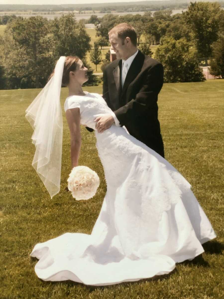 Bride leans back in dip while groom holds her and they smile at each other.