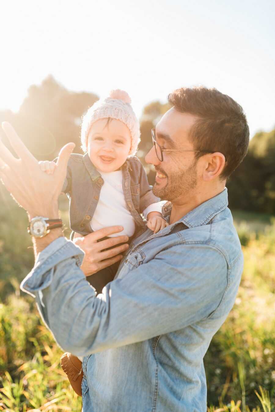 dad holds baby while giving a high five