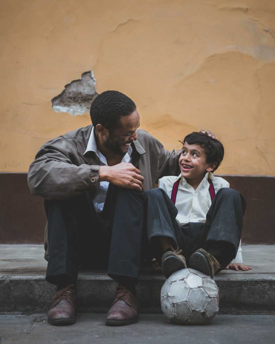 Dad site on curb with his son, looking at him