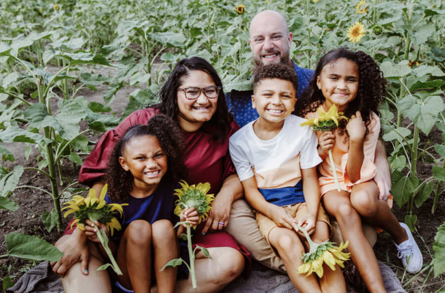 family sitting in a sunflower field 