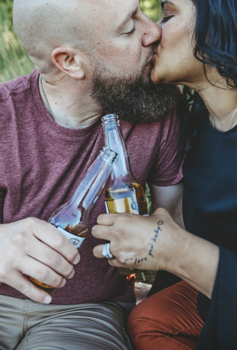 husband and wife kissing with beer in hand