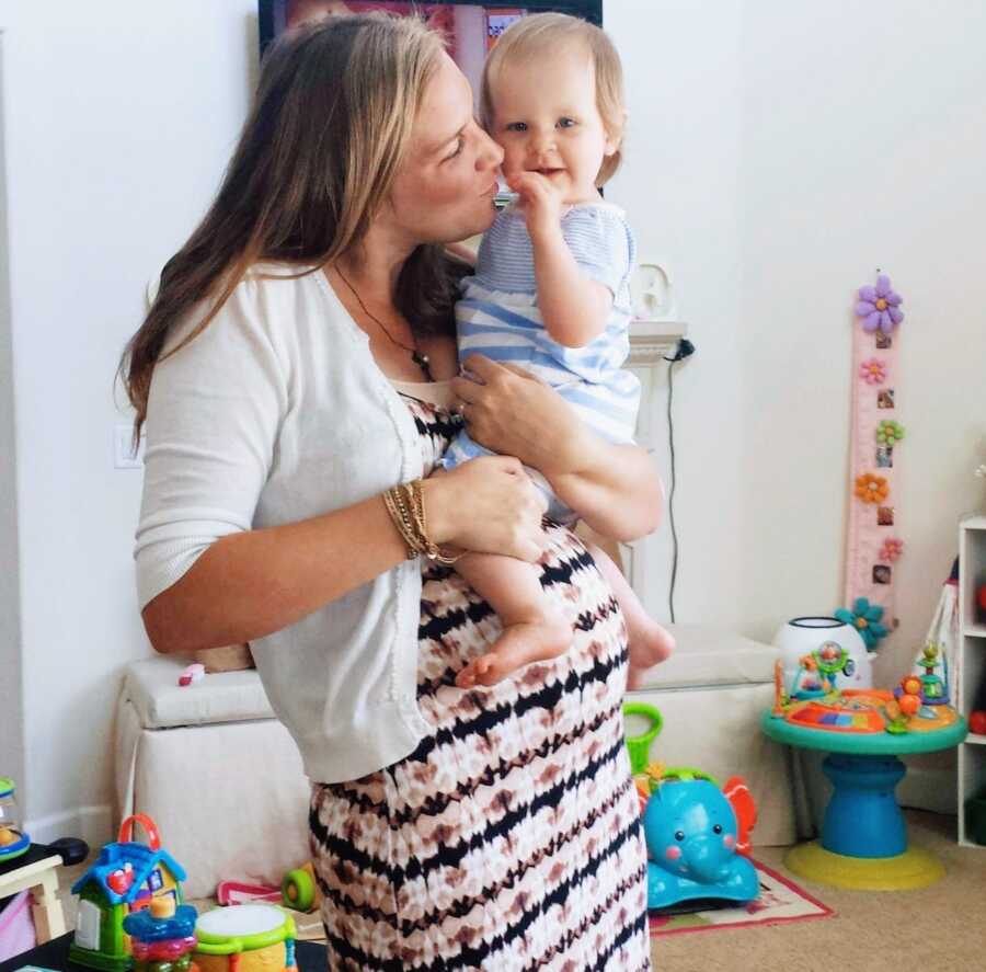 pregnant woman holding child in her arms kissing cheek 