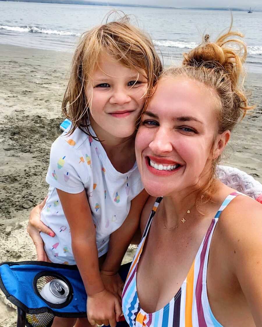 mom with daughter at beach smiling 