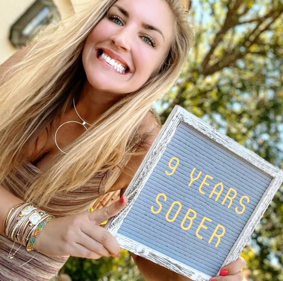 woman smiling with 9 year sober sign 