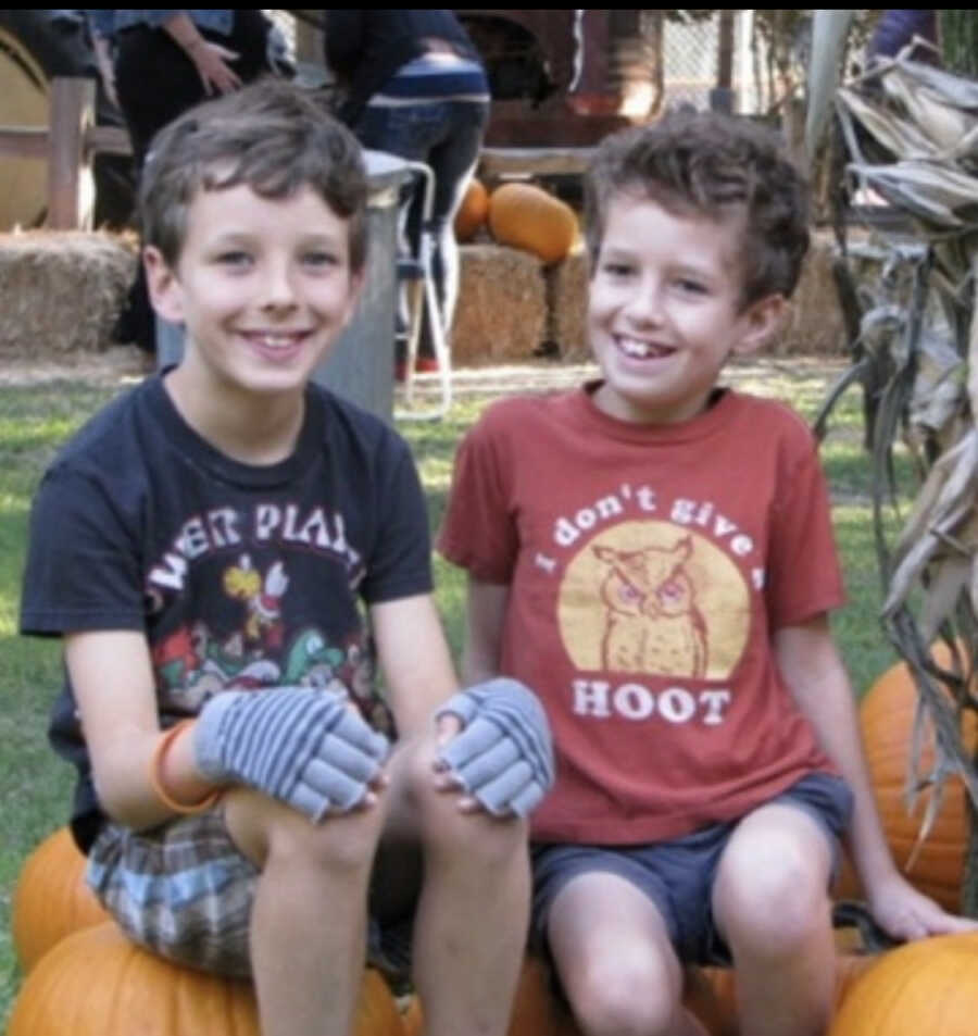 Older brother with rare genetic disease sits next to younger brother outside.