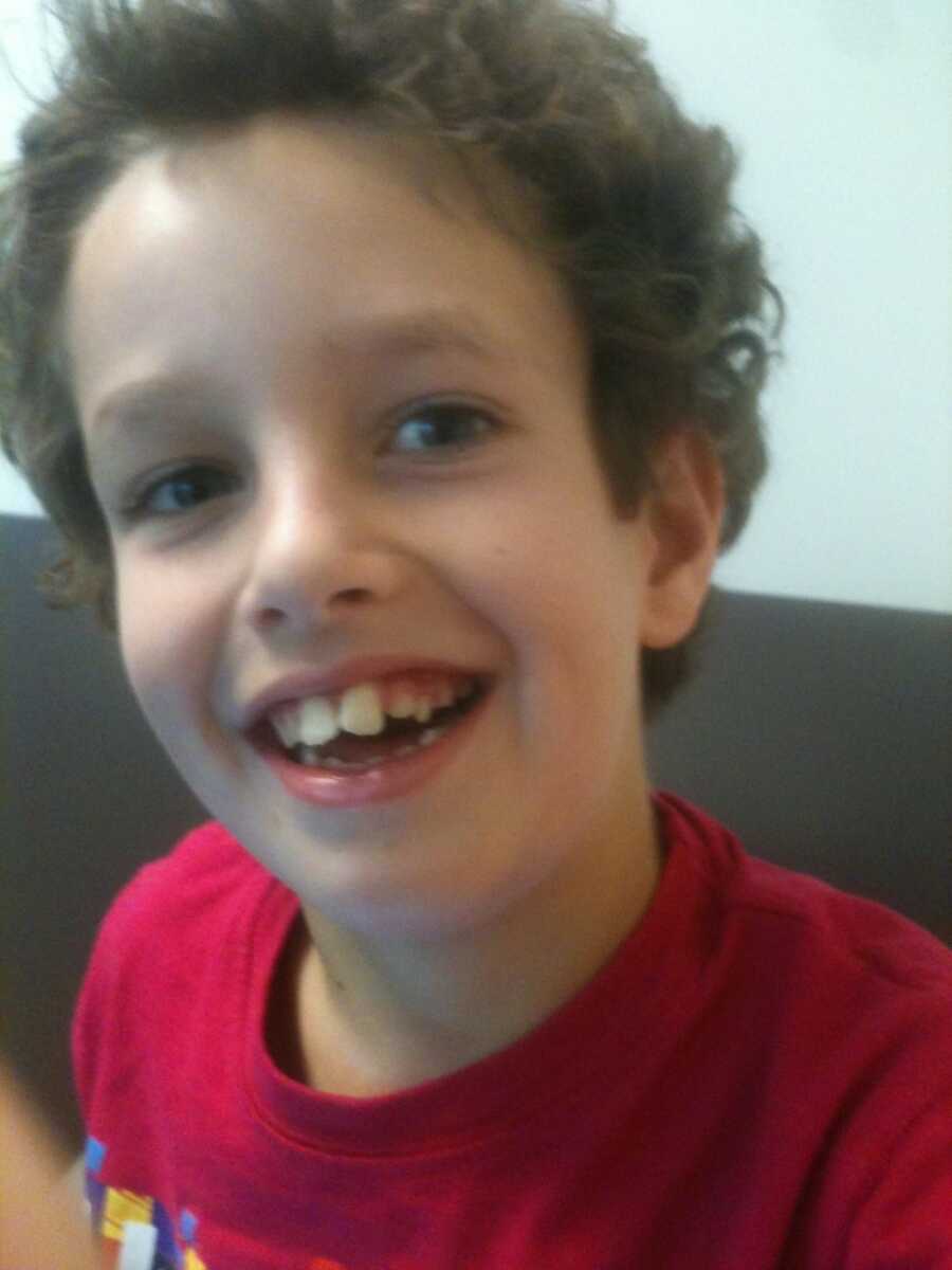 Close up picture of young curl-haired boy's smiling face.