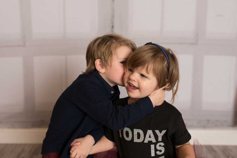 A brother kisses his adopted little sister on the cheek