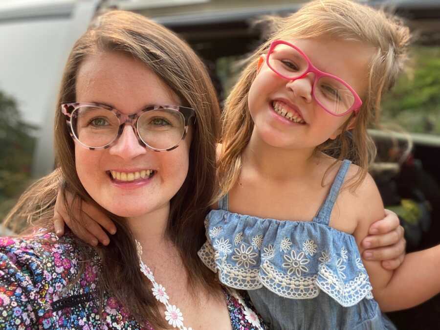 A mom and her daughter with craniofacial differences smile largely in selfie
