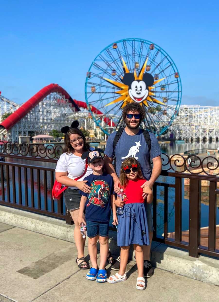 Adoptive family stands in front of Mickey Mouse ferris wheel at Disney