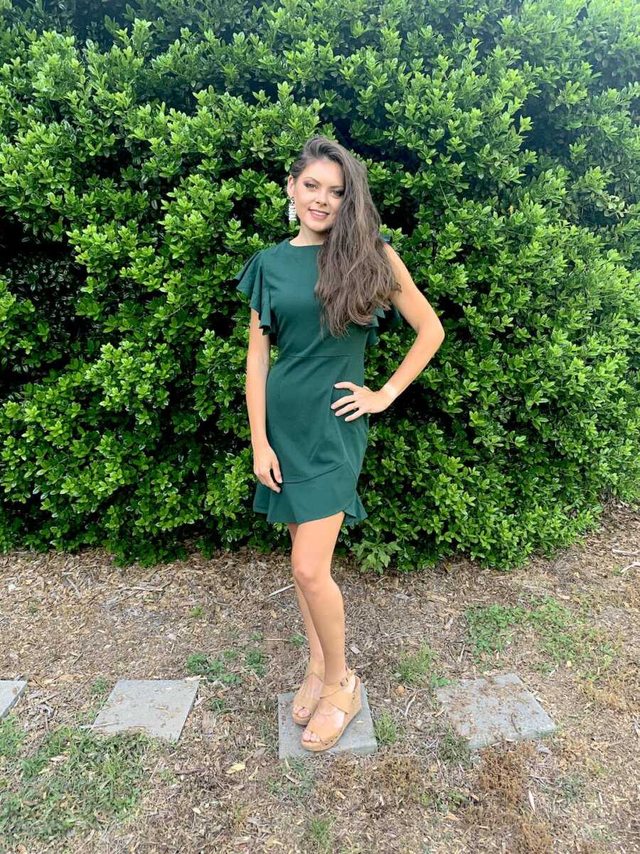 woman stands in green dress, hair and makeup done