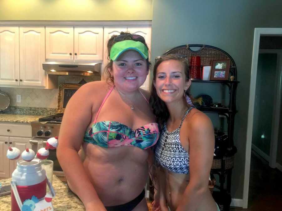 girl stands with her friend while in bathing suits