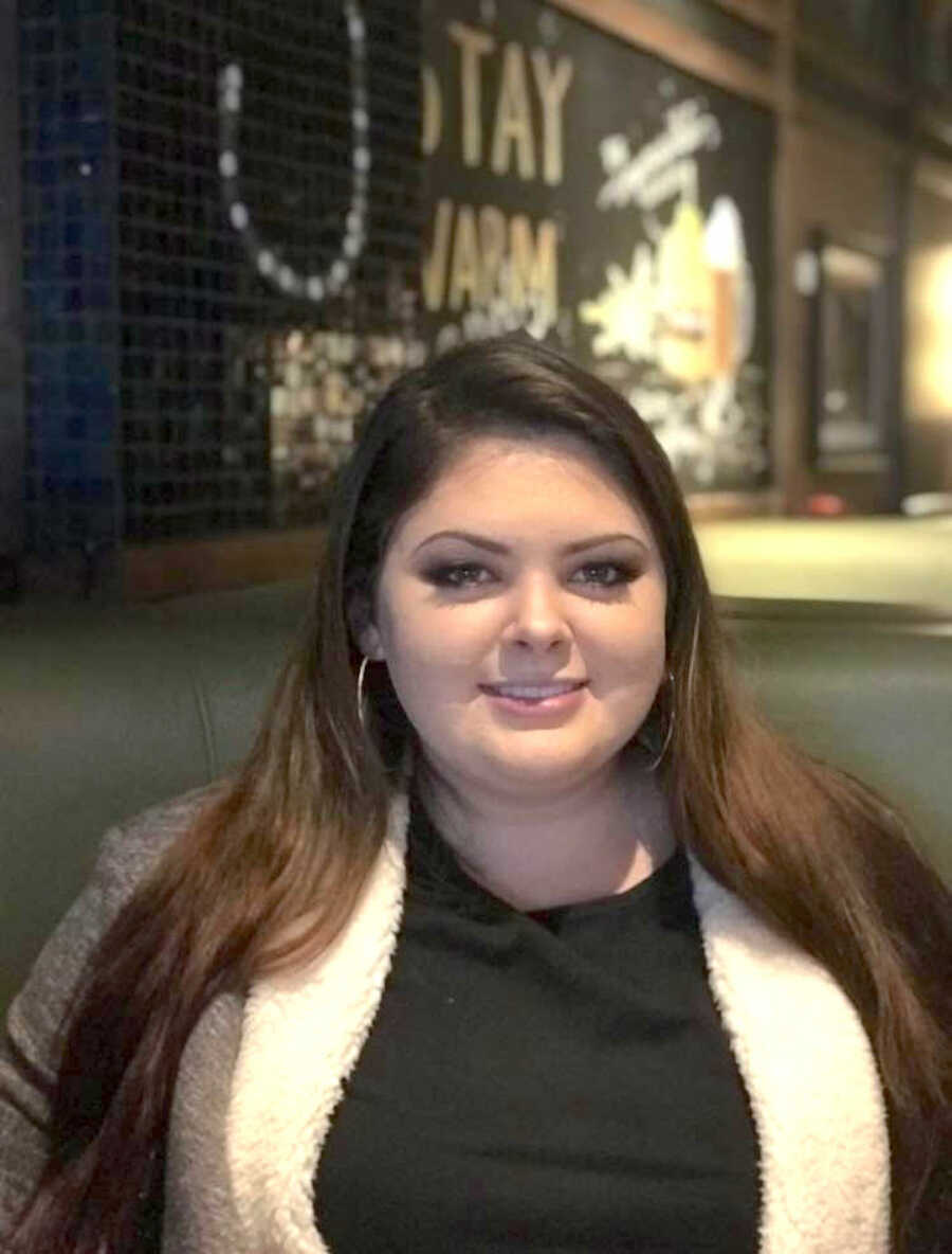 woman sits at table in restaurant smiling softly