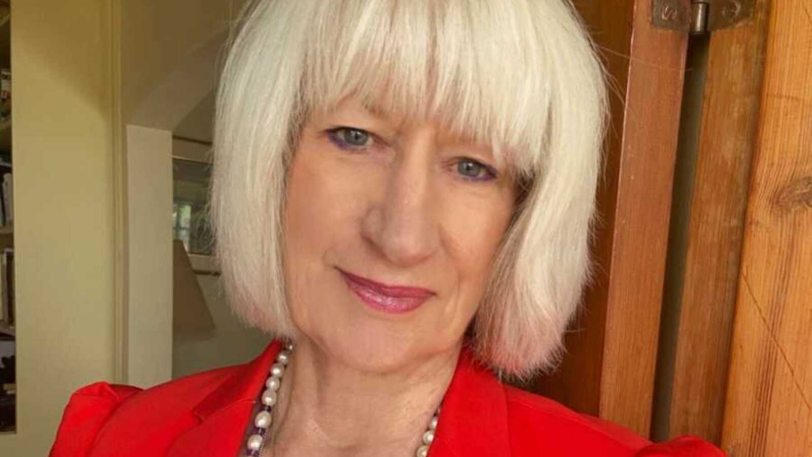 A woman with white hair wearing a red jacket