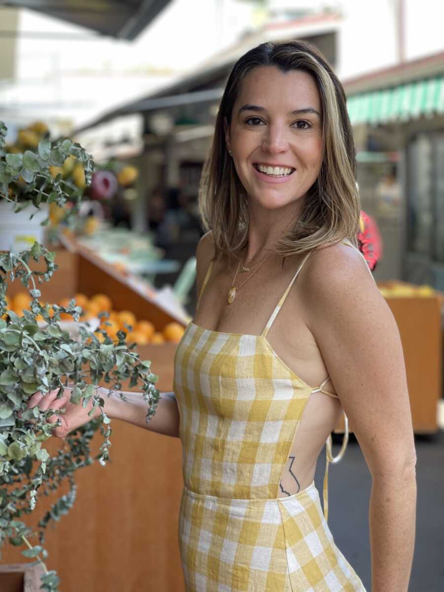 A woman in a gingham dress smiles at a market