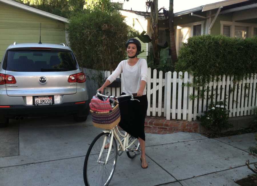 A woman stands in her driveway with a bike.