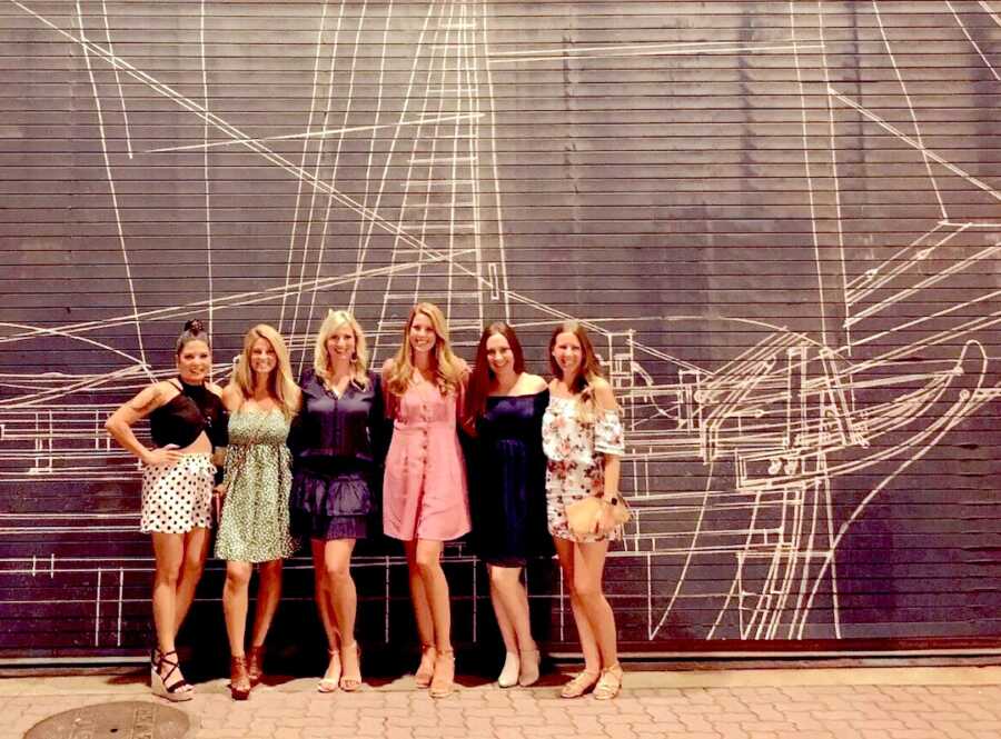 moms on a girl trip posing in front of a mural