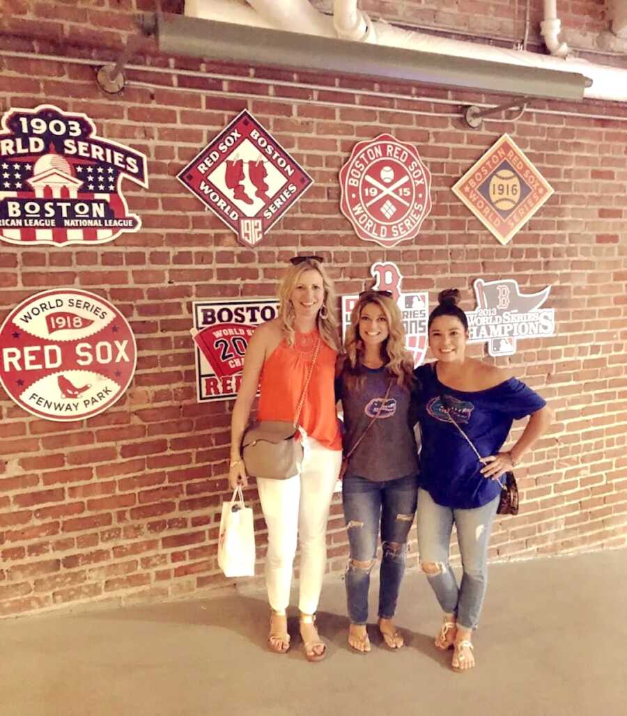 three friends stand together at a baseball game