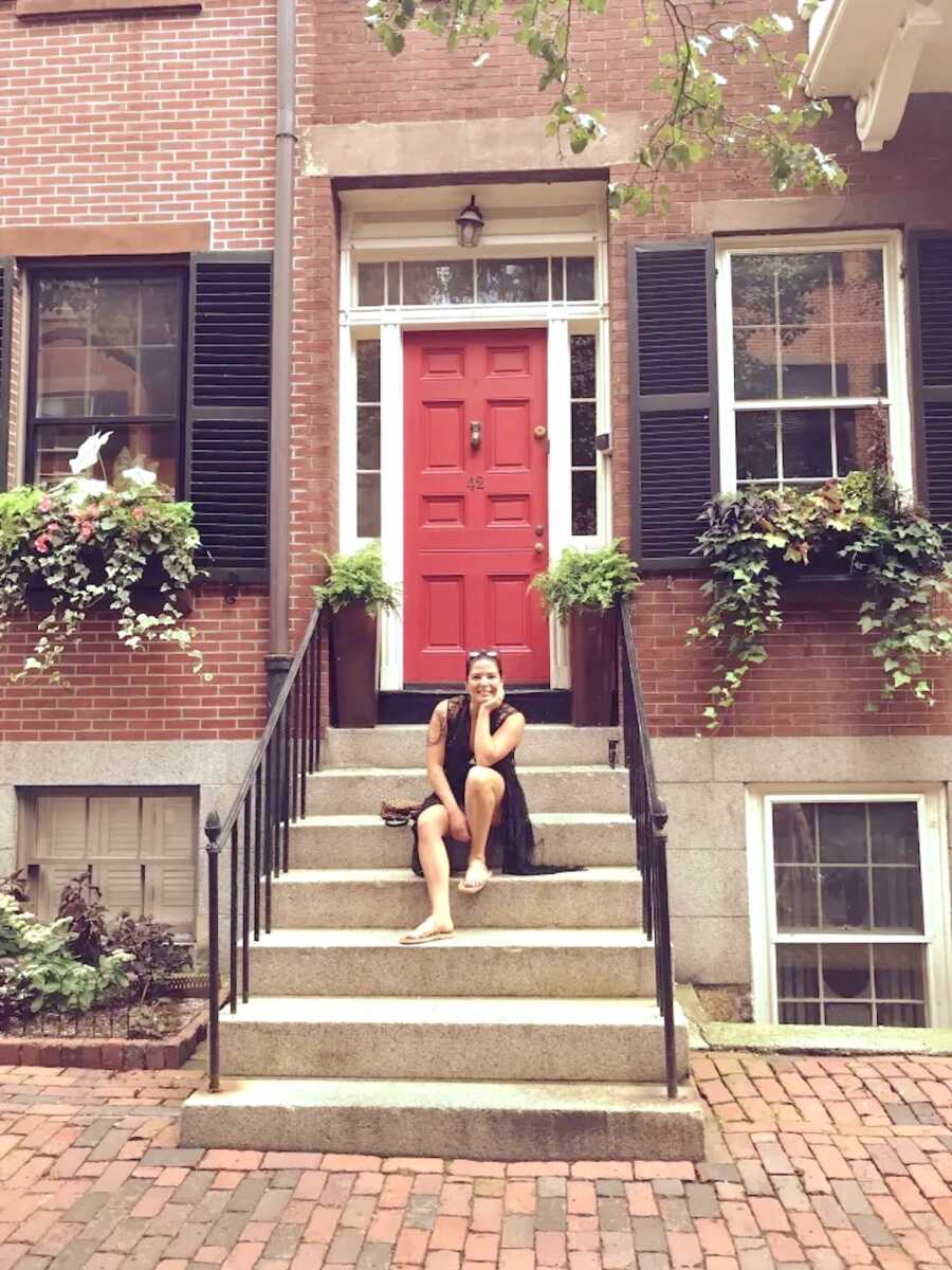 mom on girls trip sits on steps in front of a red door
