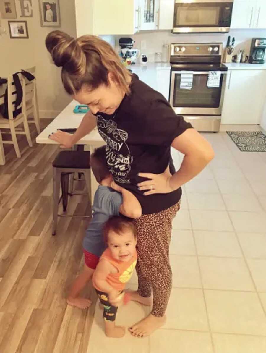 Toddlers cling to mom's legs and waist.
