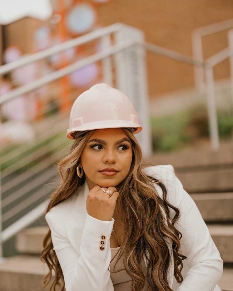 A girl poses with a pink hard had on