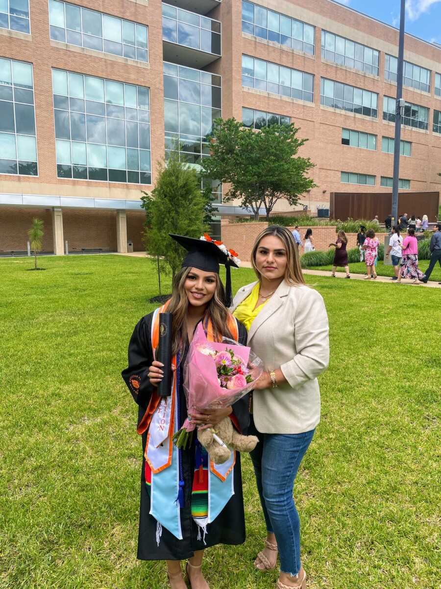 A girl in graduation regalia poses with her mom