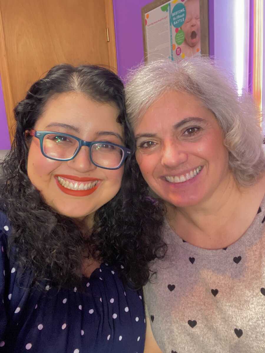 A mom and daughter smile with their heads close together