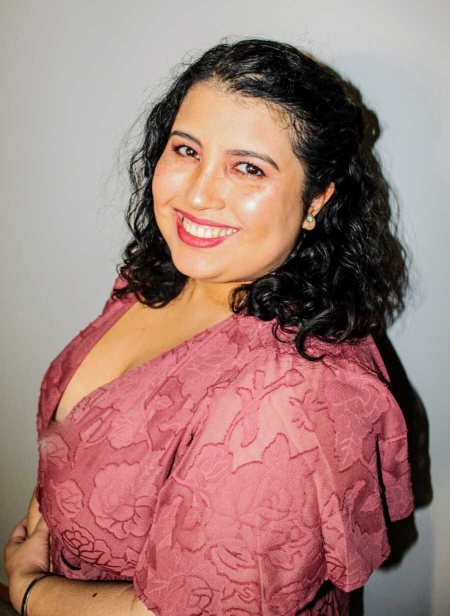 A woman smiles in a pink shirt for a headshot
