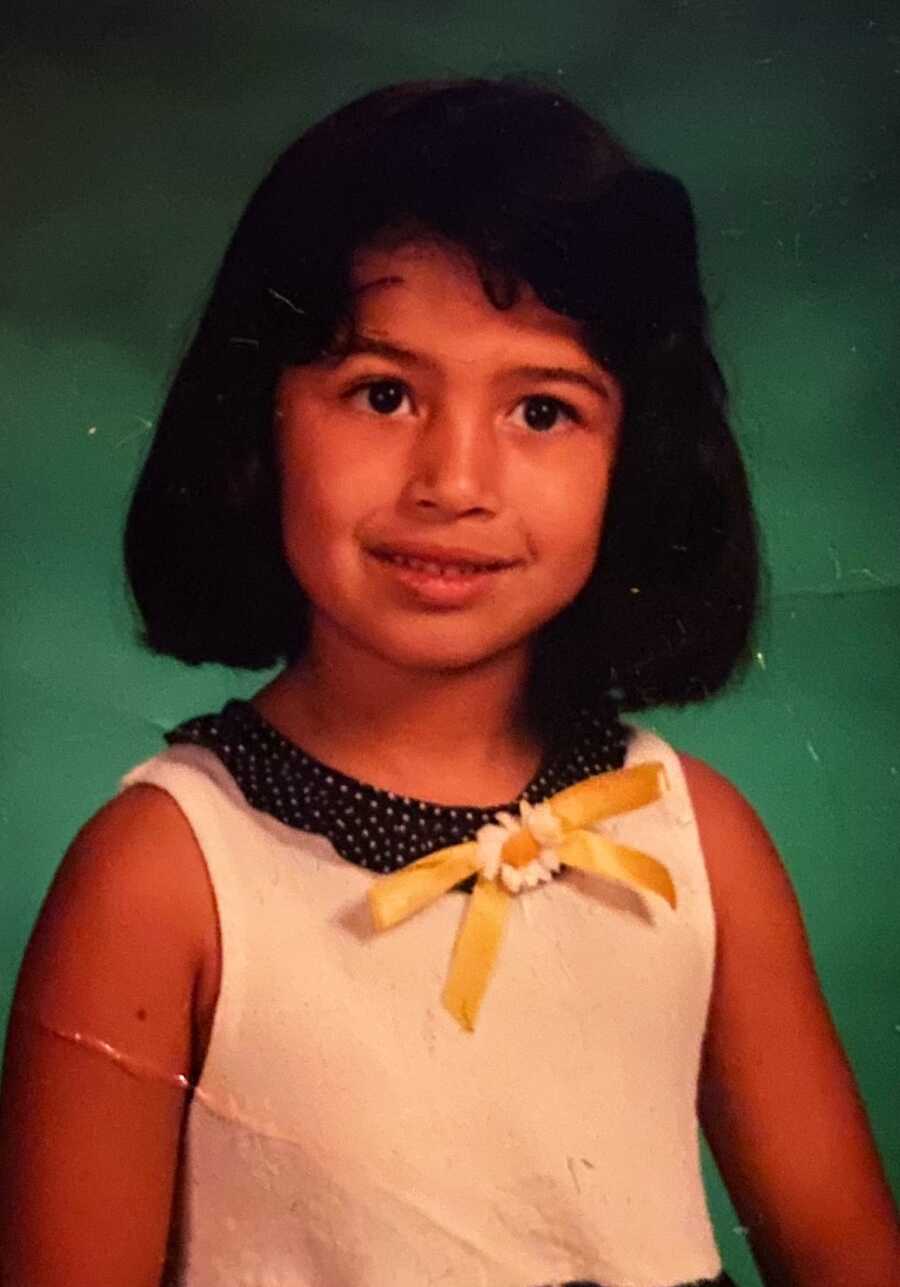 A school photo of a young girl smiling in a white dress