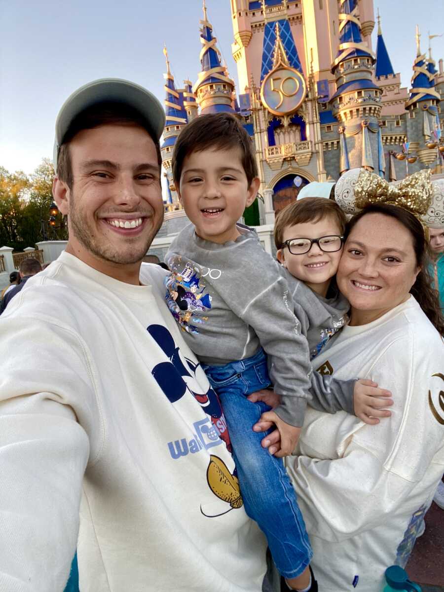 Parents and two young boys take family picture at Disney World.