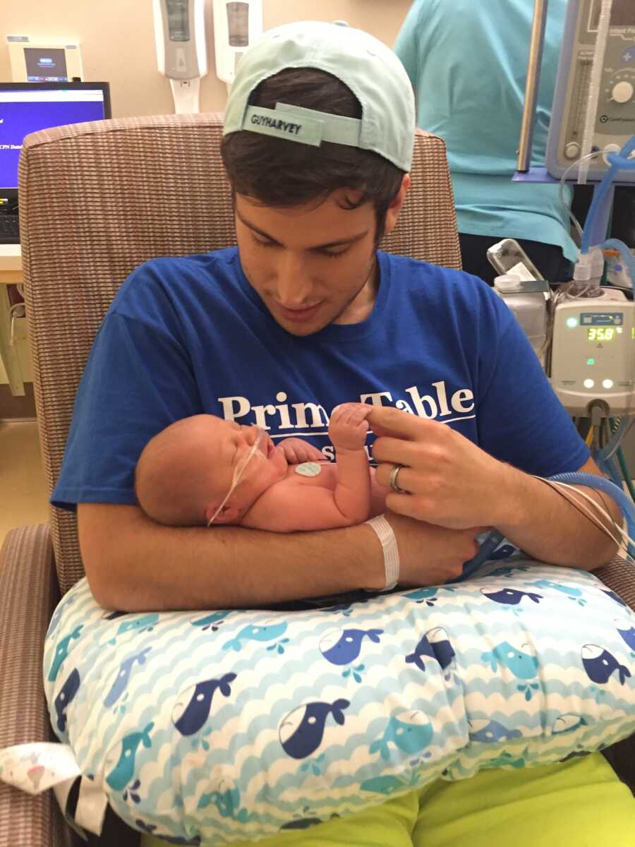 New dad holds baby in his arms at the hospital.