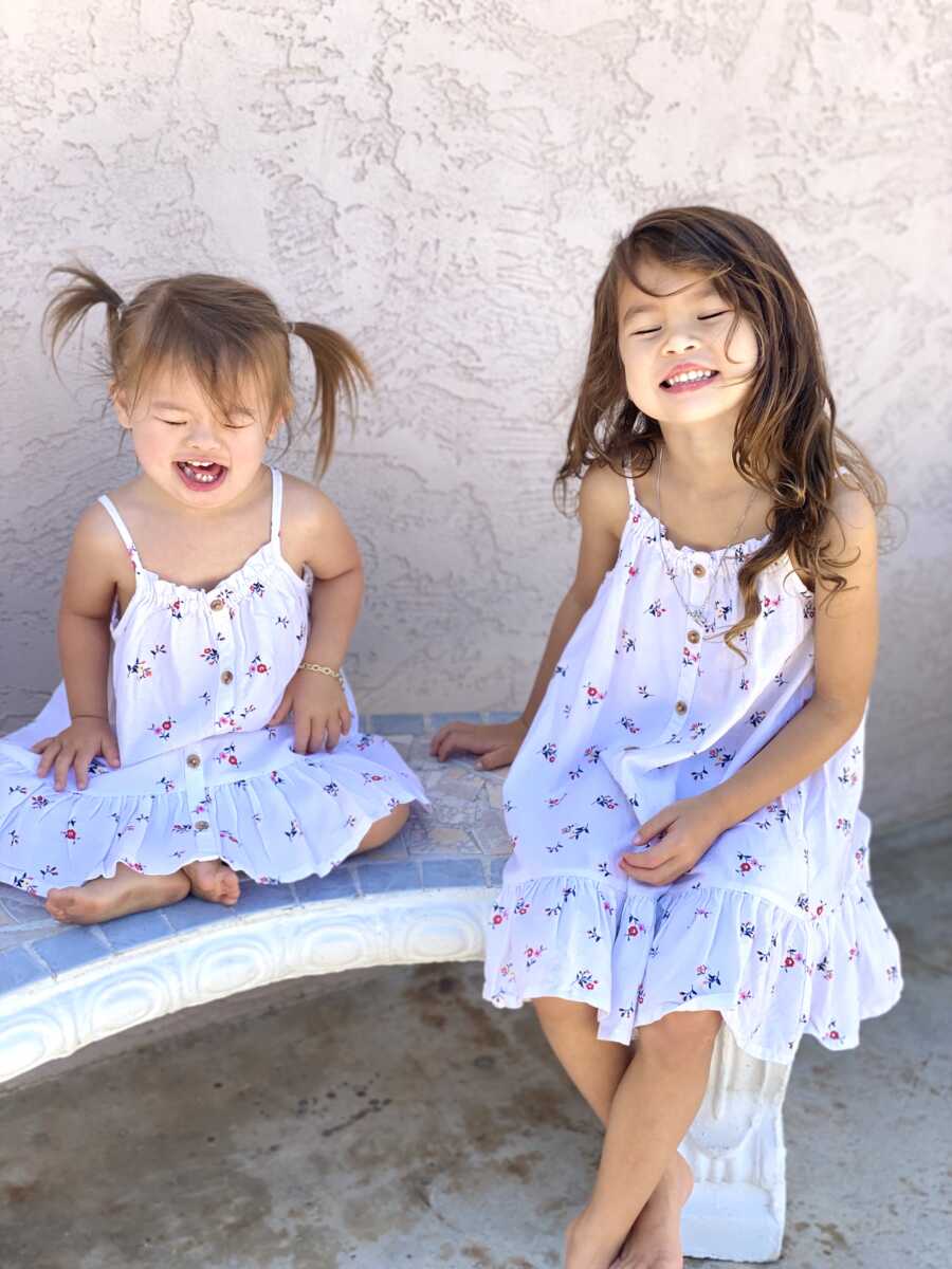 sisters sitting together for a picture in matching dresses