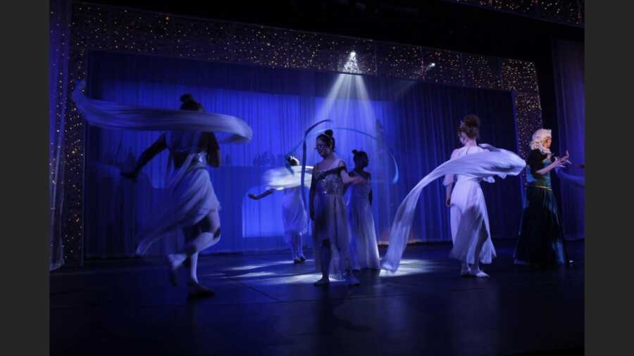 Student actors dance on stage in inclusive theatre performance.