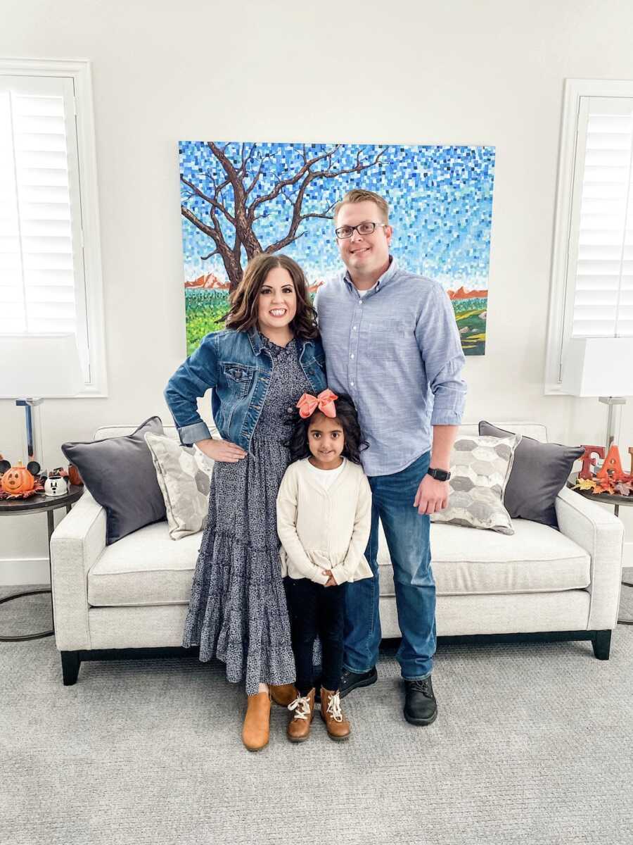 parents stand with their adopted daughter