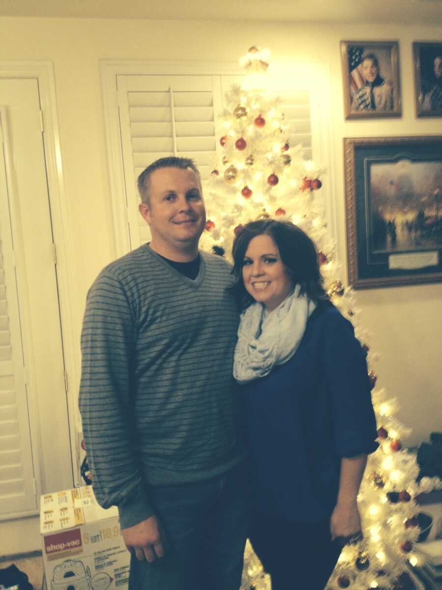 couple stands in front of a Christmas tree together