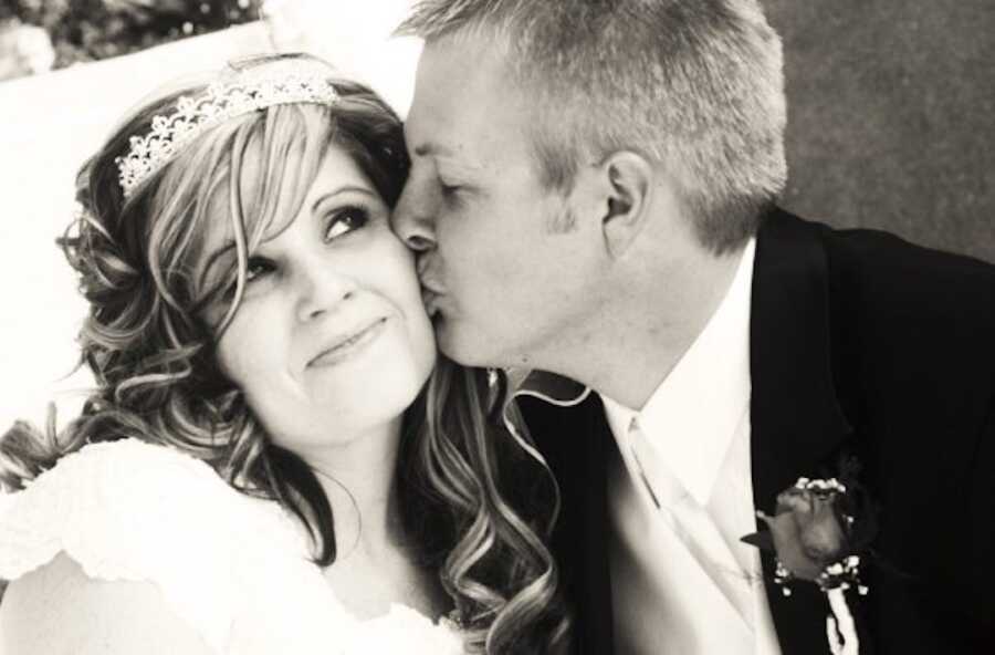 husband kisses wife's cheek on wedding day