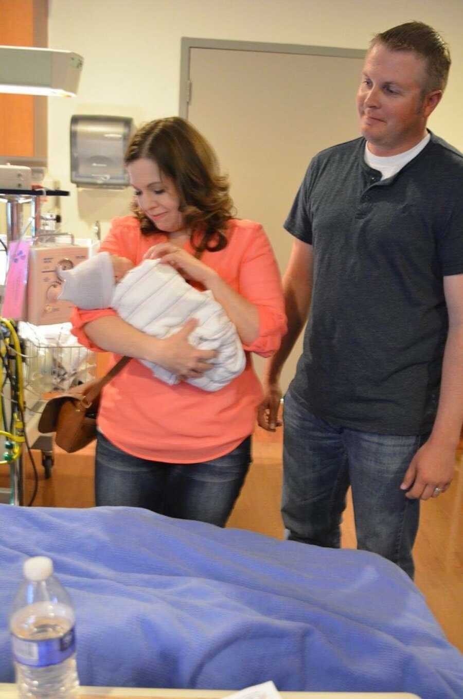 mom holds baby in hospital, dad watches