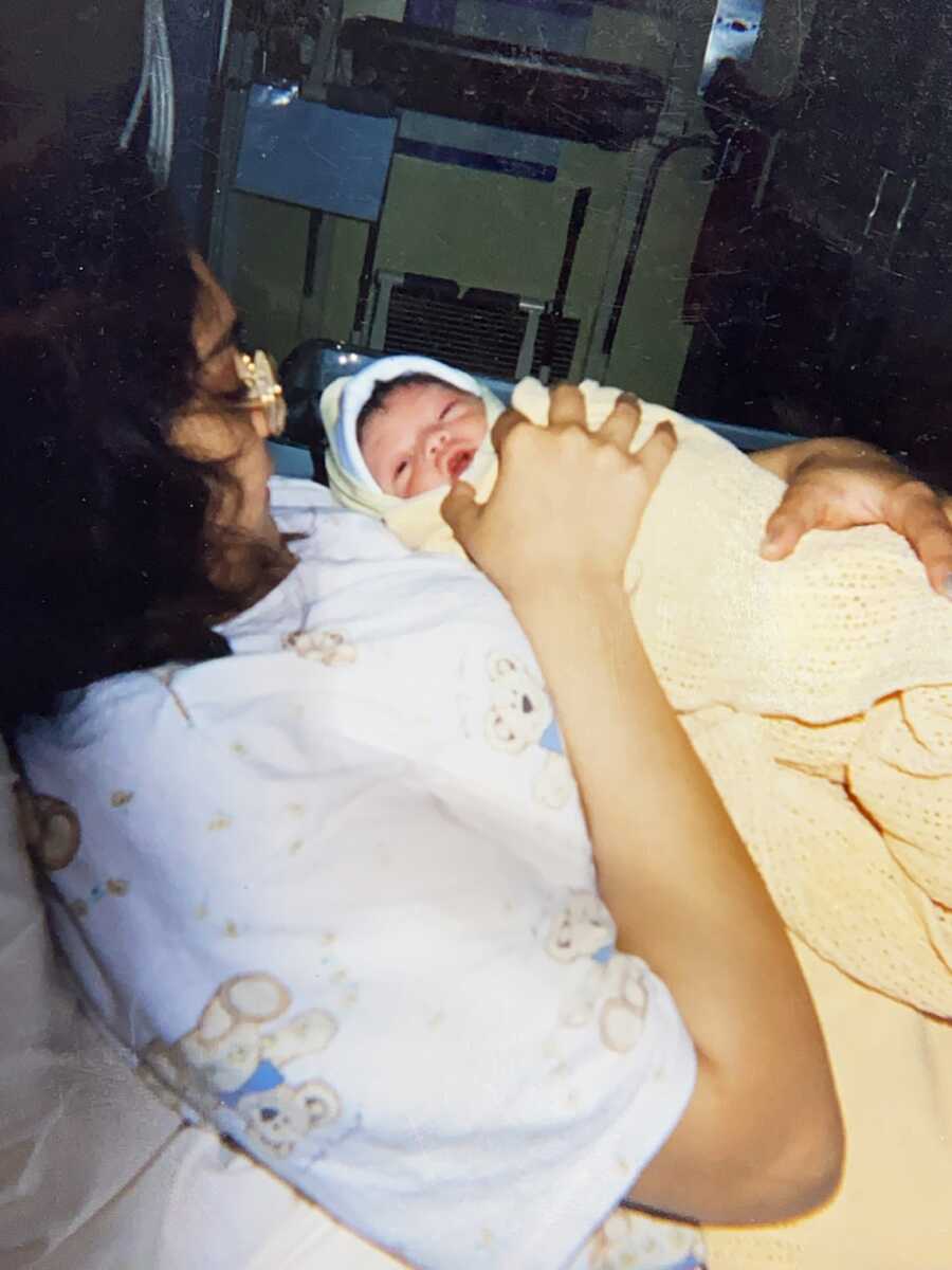 Domestic violence survivor in hospital bed holding newborn baby boy