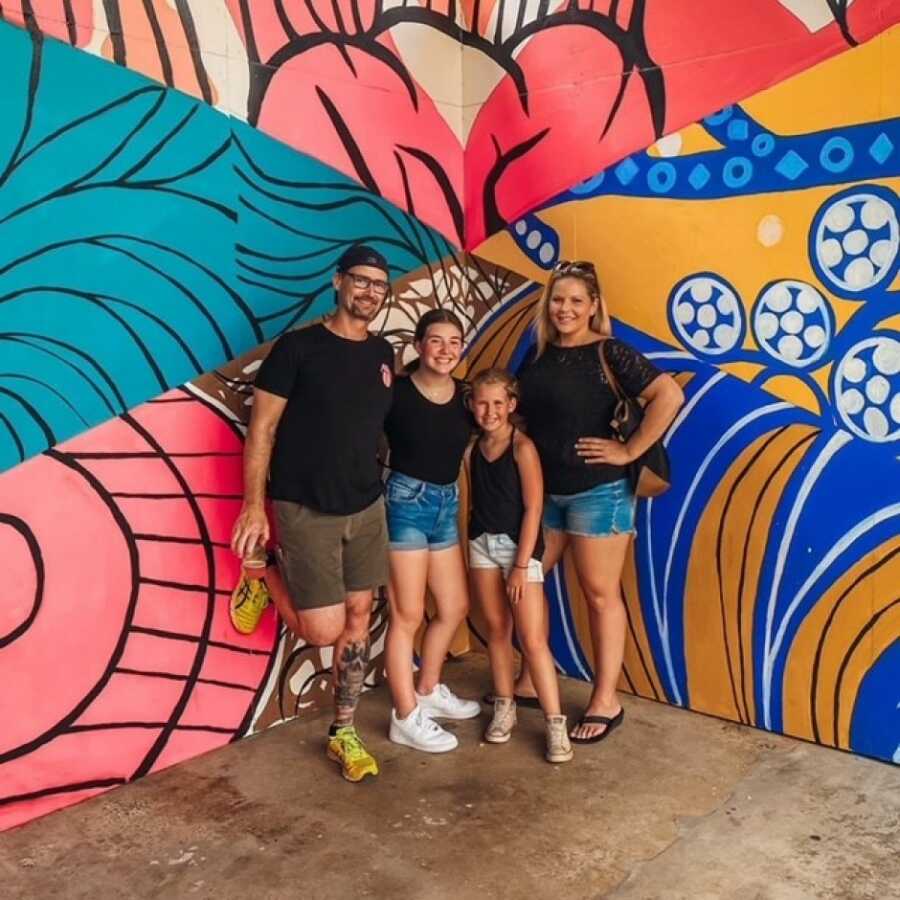 family in front of a mural