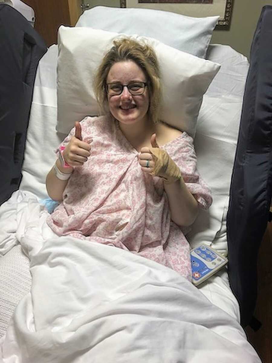 Pregnant woman sitting in hospital bed before labor with thumbs up