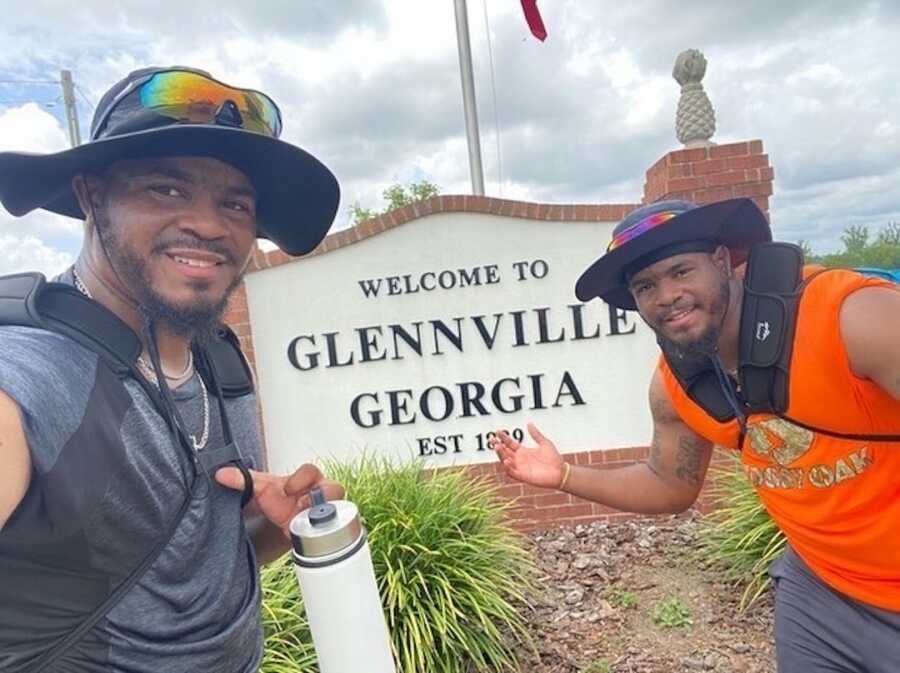 Brothers in front of town sign 