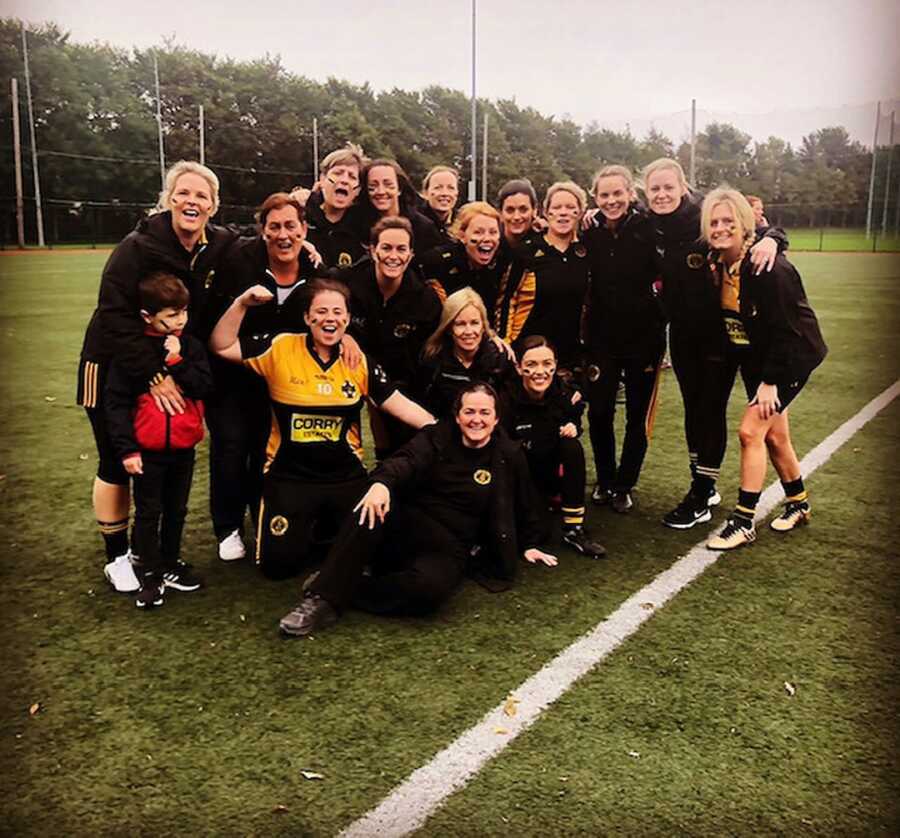 Young woman takes picture on field with football team.