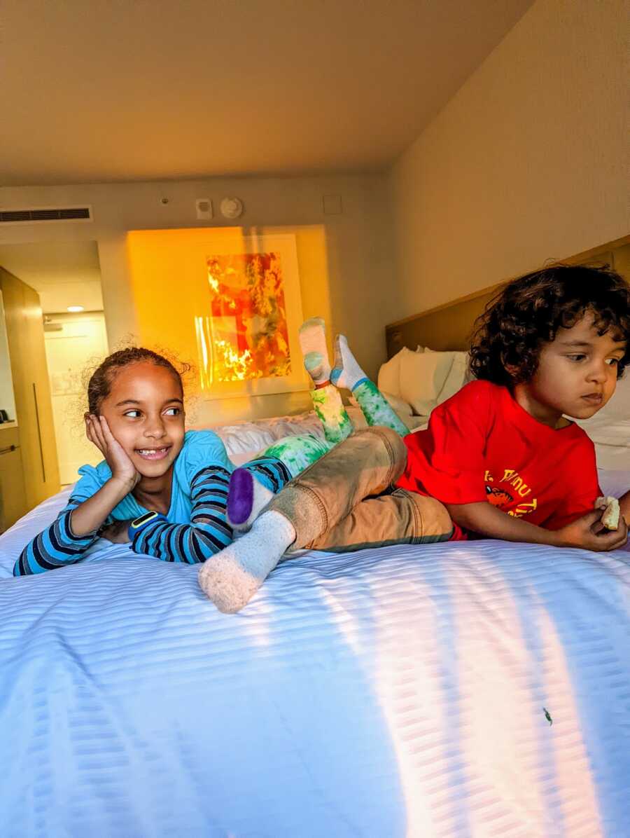 Sister and autistic brother lying on hotel bed