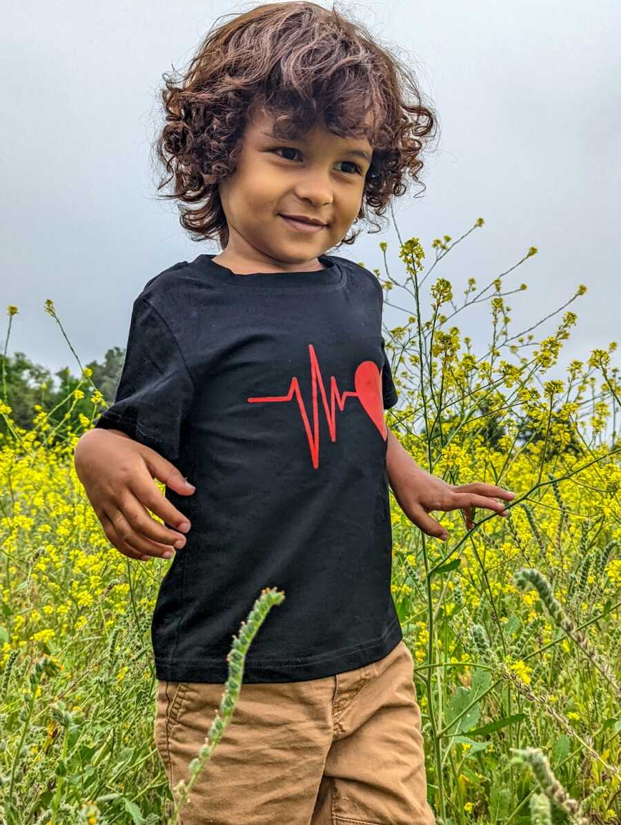 autistic boy standing in field of yellow flowers