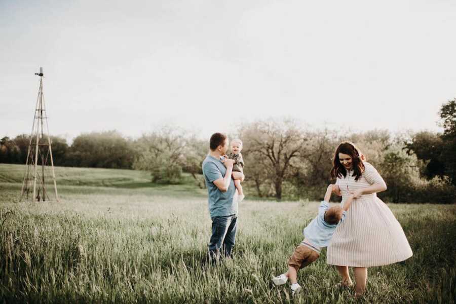 Young family takes candid picture in field.